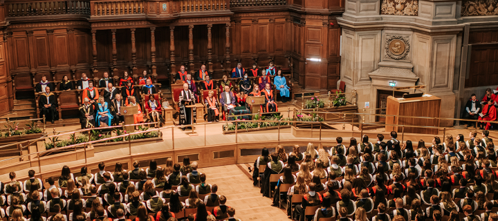 Wide shot of McEwan hall during graduations. Senior leadership team sit up front with rows of graduating students in the foregro